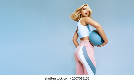 Back view of beautiful girl stretching body holding ball. Female in leggins and white topic sportswear. Copy free space, fitness and sport concept picture. - Shutterstock ID 2007018155