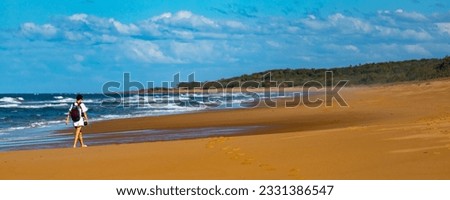 back view of a beautiful hiker girl in white dress walking on an endless beach in deepwater national park, south from agnes water and seventeen seventy in gladstone region, queensland, australia	