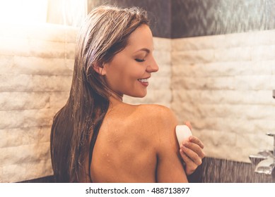 Back View Of Beautiful Naked Woman Using A Soap And Smiling While Taking Shower In Bathroom