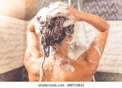 Back View Of Beautiful Naked Young Woman Is Using Shampoo While Taking Shower In Bathroom