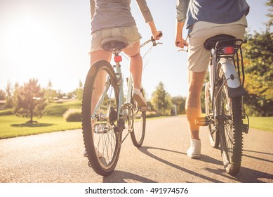 Back view of beautiful stylish couple cycling in the park, cropped