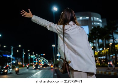 Back View, Beautiful Woman Smiling Using Smartphone Application Hailing With Hand Up Calling Cab Outdoor After Late Work, Asian Business Woman Hail Waving Hand Taxi On Road In City Street At Night