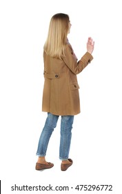 Back View Of Beautiful Woman Welcomes. Blonde In A Brown Coat Stands And Waving Hand.