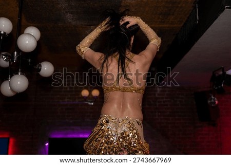 Back view of belly dancer performing on stage.