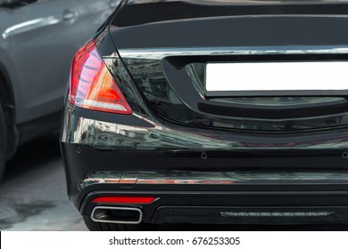 Back View Of Big Luxury Expensive Sedan Car Trunk. Black Colored. LED Red Tail Lights . Empty License Plate With Place For Text.