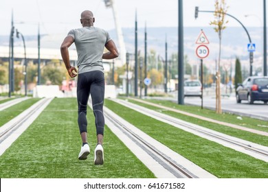 Back View Of Black Man Running In Urban Background. Young Guy Doing Workout Outdoors.