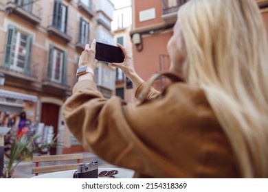 Back View Of Blonde Woman Holding Smartphone Outside