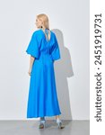 Back view of blonde woman in vibrant long blue dress