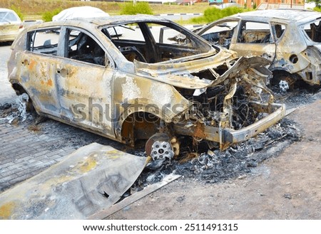 A back view of a blown up down car. A charred burned down vehicle in the city center in residential area. Absolutely destroy sedan car in the parking lot after the bombing by cluster bomb.