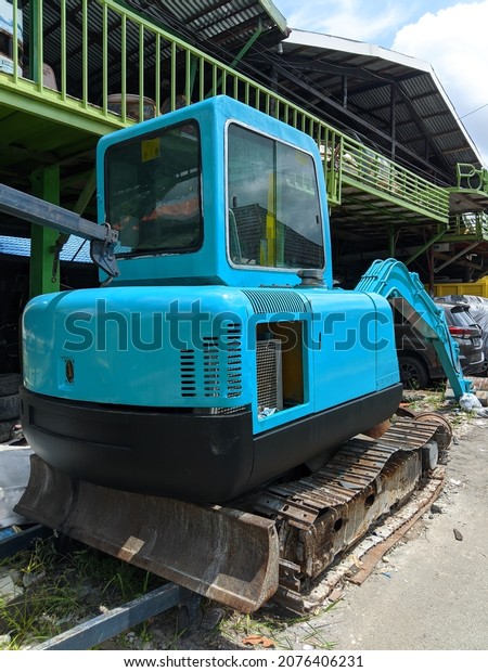 the back view of the blue excavator that is no\
longer in use because it is\
damaged