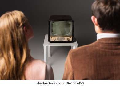 Back View Of Blurred Couple Watching Retro Tv On Grey Background