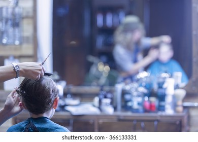 Back View Of Boy In Barber Chair. Woman Cutting Boy Hair. Unrecognizable  