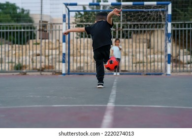 Back View Of Boy Kicking Soccer Ball. Young Girl Soccer Goalkeeper Warding The Football Goal.