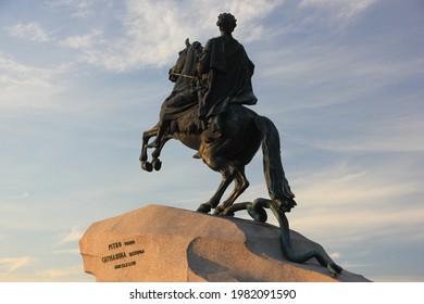 Back view of the Bronze Horseman statue of Peter the Great situated in the Senate Square in St. Petersburg in Russia, the statue in illuminated by golden sunlight, blue cloudy sky is in the background