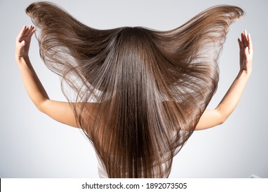 Back View Of A Brunette Woman With A Long Straight Hair. Young   Model With  Beautiful Hair - Isolated On White Background. Young Girl With Hair Flying In The Wind. 