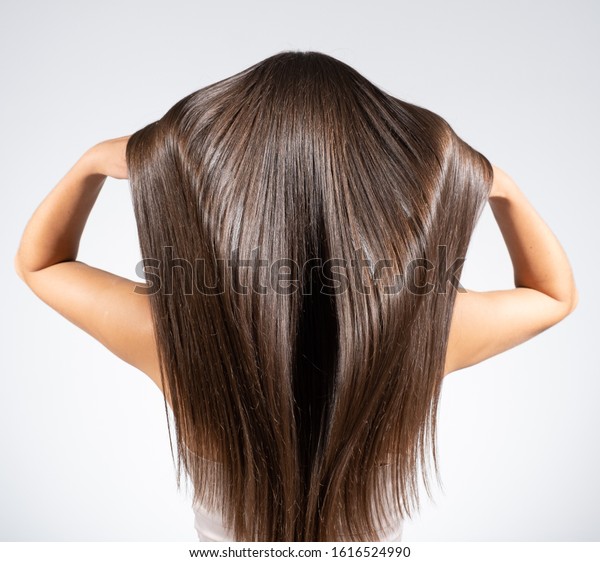Back view of a brunette\
woman with a long straight hair. Young   model with  beautiful hair\
- isolated on white background. Young girl with hair flying in the\
wind. 
