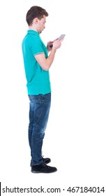 Back View Of Business Man Uses Mobile Phone.    Rear View People Collection. Isolated Over White Background. Backside View Of Person. Curly Man In A Turquoise Sweater Standing Sideways And Looking At