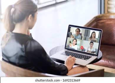 Back view of business woman talking about sale report in video conference. Asian team using laptop and tablet online meeting in video call.Working from home, Working remotely and Self isolation.