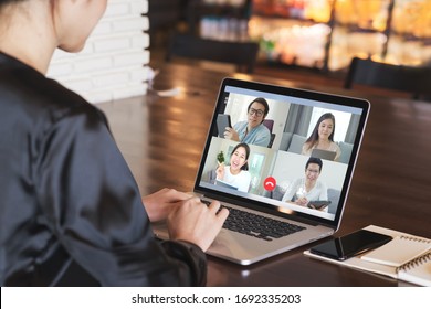 Back view of business woman talking about sale report in video conference. Asian team using laptop and tablet online meeting in video call.Working from home, Working remotely and Social isolation. - Powered by Shutterstock