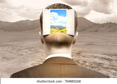 Back view of businessman with abstract open door and landscape view in head on desert background. Opportunity concept 