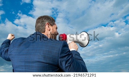 back view of businessman agitate in loudspeaker on sky background