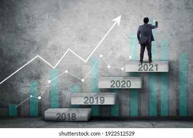 Back View Of Businessman Drawing Upward Arrow And Growth Chart While Standing On The Stair With Numbers 2021