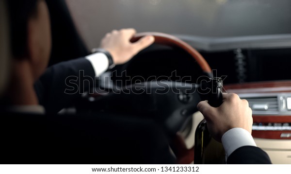 Back view of businessman drinking alcohol in car\
before driving home,\
problems