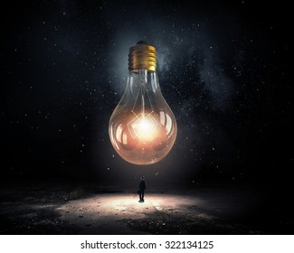 Back view of businessman looking at big light bulb