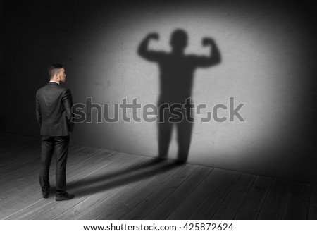 Back view of businessman looks to his shadow with strong his display in future. Believe in yourself. Success and development. Setting and achieving goals. The look into the future.