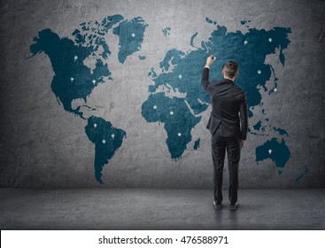 Back view of a businessman making marks on world map. Global communication. International relations. Business staff. - Powered by Shutterstock