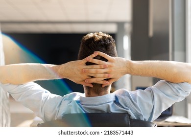 Back view of businessman sitting in office chair hands over heads working at laptop, male manager stretching looking at computer screen, man taking break distracted from job - Powered by Shutterstock