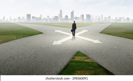 Back View Of Businessman Standing At Crossroads And Making Choice