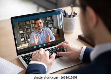 Back view of businessman talk with male business partner using video call on laptop discuss work project online, male client talk with colleague or coworker, speak on webcam conference on computer