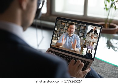 Back View Of Businessman Talk On Video Call On Laptop With Multiracial Employees Or Colleagues, Male Boss Have Webcam Conference Or Virtual Event With Diverse Businesspeople, Use Internet On Computer