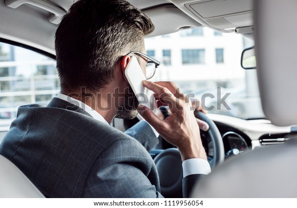 back view of businessman talking on smartphone while\
driving car