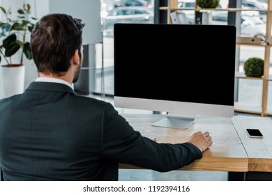 Back View Of Businessman At Workplace With Computer Screen With Blank Screen In Office