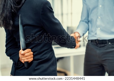Back view of businesswoman shaking hands with another businessman while holding a knife behind his back. Concept of back backstabbing in business, backstabbing between colleagues.
