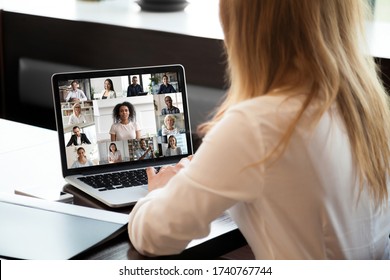 Back view of businesswoman sit at desk have video call with multiracial colleagues on laptop, female employee speak talk on webcam conference on computer, brainstorm with coworkers at meeting online - Shutterstock ID 1740767744