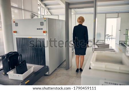 Back view of businesswoman in skirt suit passing through check-in gate before the flight