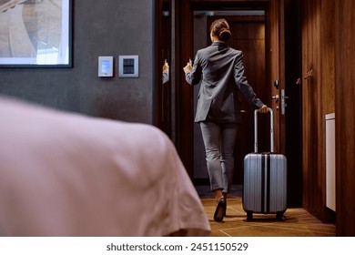 Back view of businesswoman with travel bag leaving her hotel room. Copy space. - Powered by Shutterstock