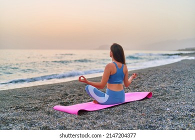 Back view of calm serene bliss satisfied fitness woman doing yoga meditation and breathing exercises on the beach by the sea. Mental mind care and healthy habits - Shutterstock ID 2147204377