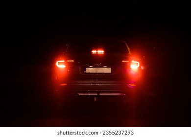 A back view of a car with red backlights at night