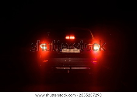 A back view of a car with red backlights at night