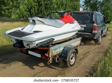 back view car with a white sport motor boat at the trailer at the green grass.  car with  powerboat  on hindcarriage