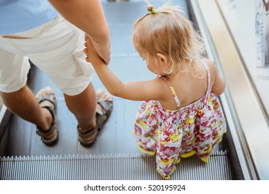 Back view of caring father walking daughter on escalator stairs background