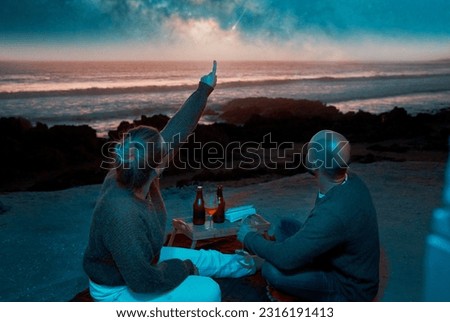 back view caucasian couple sitting in a viewpoint having picnic and watching the starry sky over the ocean