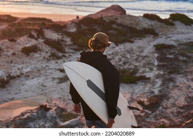 Back view of the caucasian man walking with surfboard at the rocky hill - Powered by Shutterstock