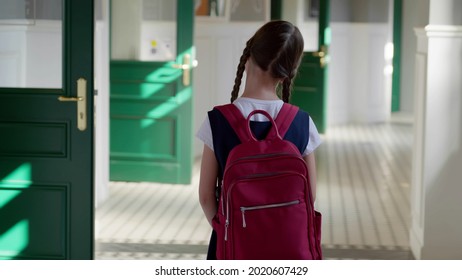 Back view of caucasian schoolgirl with backpack standing in school corridor. Rear view of preteen kid student with schoolbag standing on empty hallway - Powered by Shutterstock