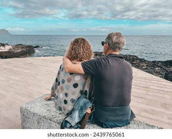 Back view of caucasian senior couple sitting face the sea enjoying freedom and vacation, two mature people stay together. Horizon over water - Powered by Shutterstock