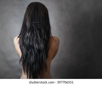 Back View Of A Caucasian Woman With Beautiful Black Hair On Dark Background.